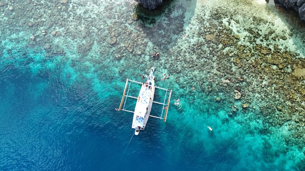 Luchtfoto van een aangemeerde bangka boven koraal in helder water bij Coron