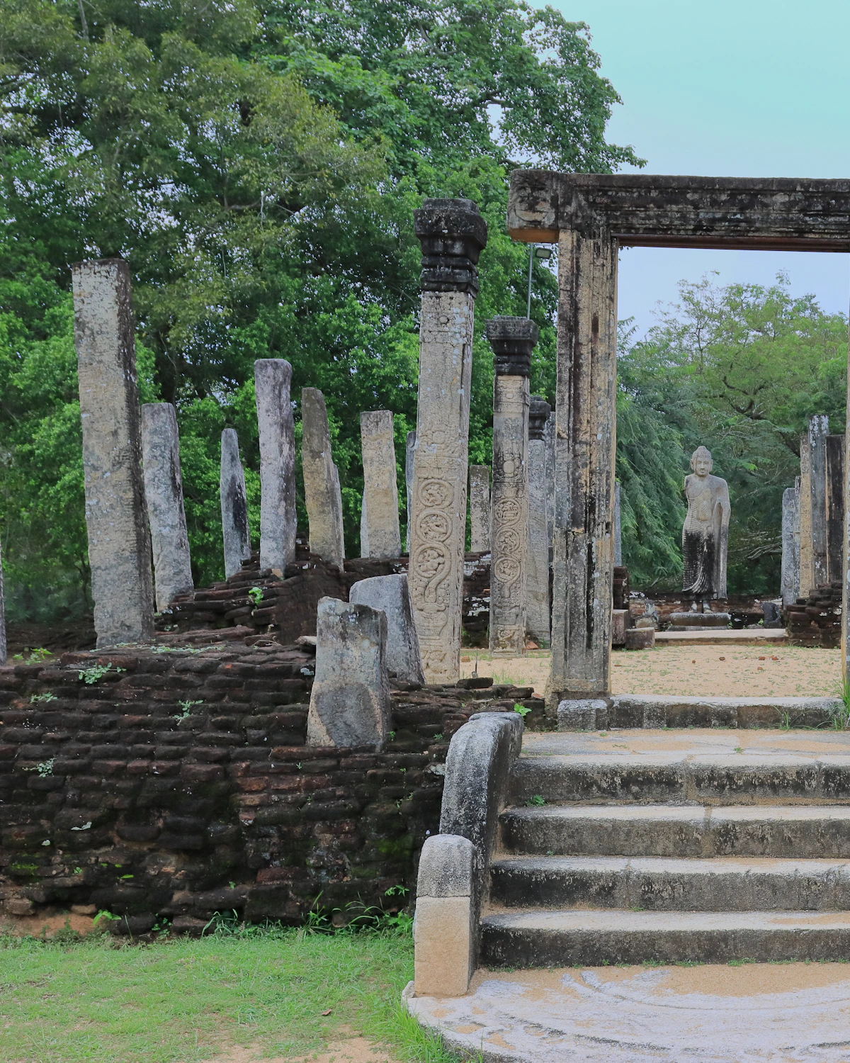 Stenen pilaren rond een Boeddhabeeld in het ruïnecomplex van Polonnaruwa