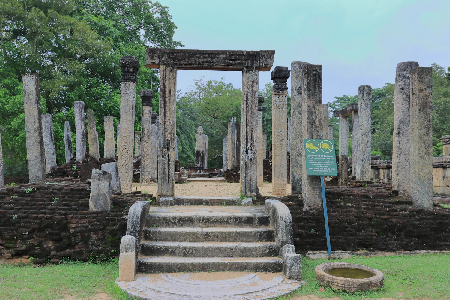 Stenen pilaren rond een Boeddhabeeld in het ruïnecomplex van Polonnaruwa