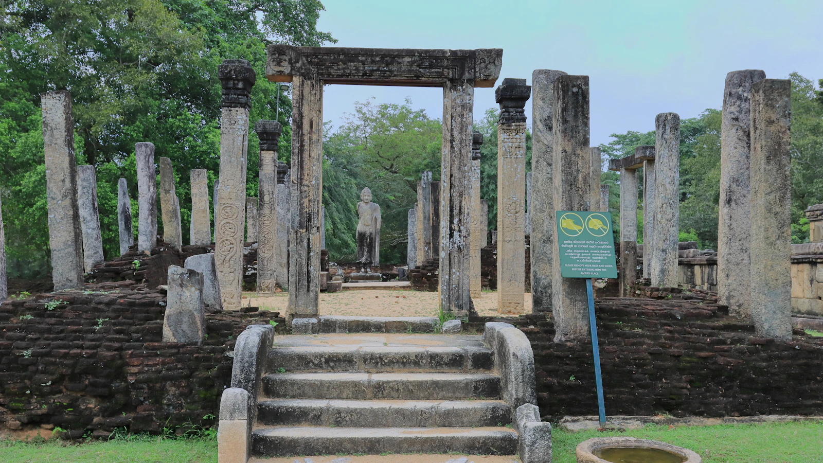 Stenen pilaren rond een Boeddhabeeld in het ruïnecomplex van Polonnaruwa