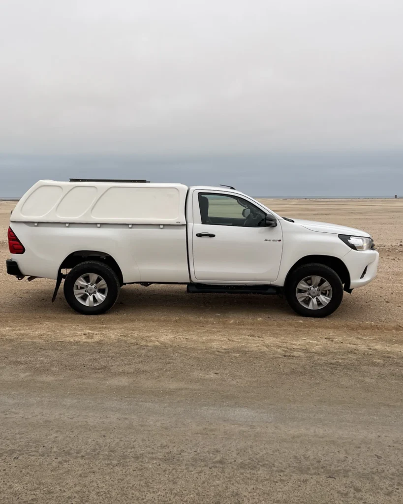 Witte pickup-truck in het woestijnlandschap van Namibië