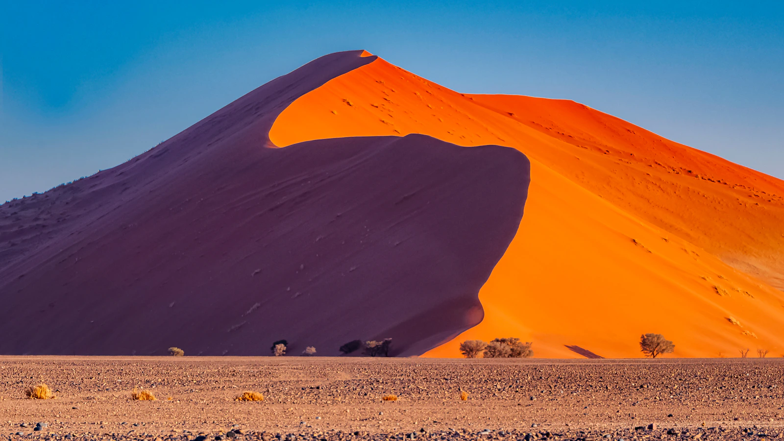 Bruine zandduinen onder de blauwe hemel van Sossusvlei