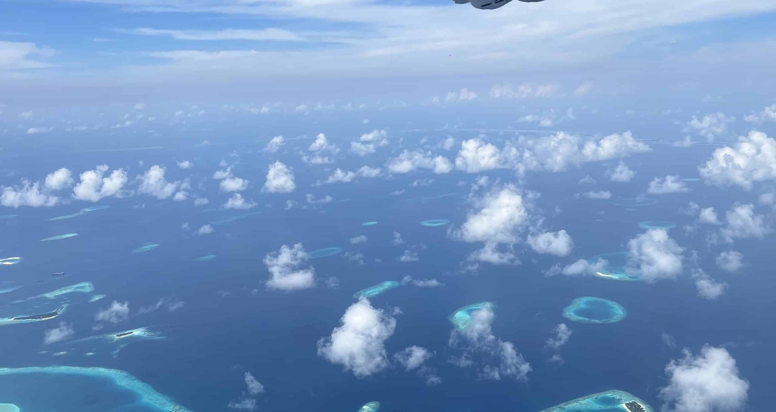 Brede luchtfoto van de atollen en riffen van de Malediven met wolken erboven