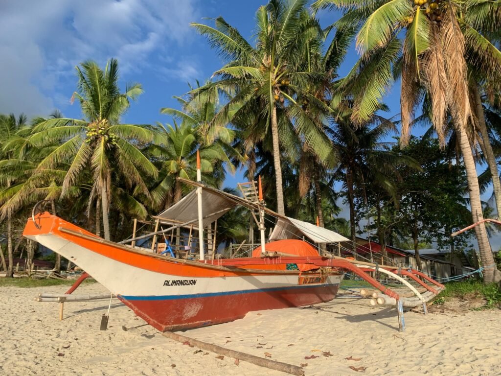 Bangka op een strand met kokospalmen in San Vicente op Palawan
