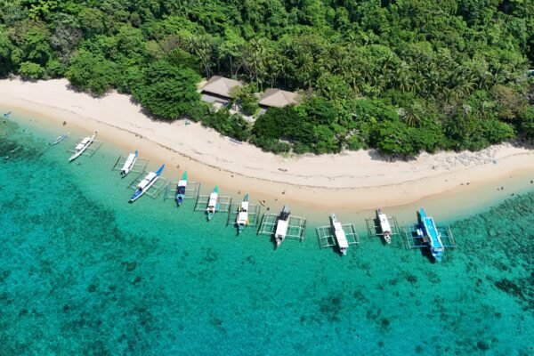 Luchtfoto van bangkaboten die aangemeerd liggen op een turquoise strand bij El Nido in de Filipijnen