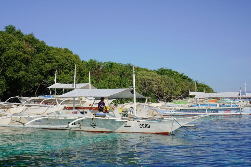 Bangka’s in helder water langs een groene kust op Cebu