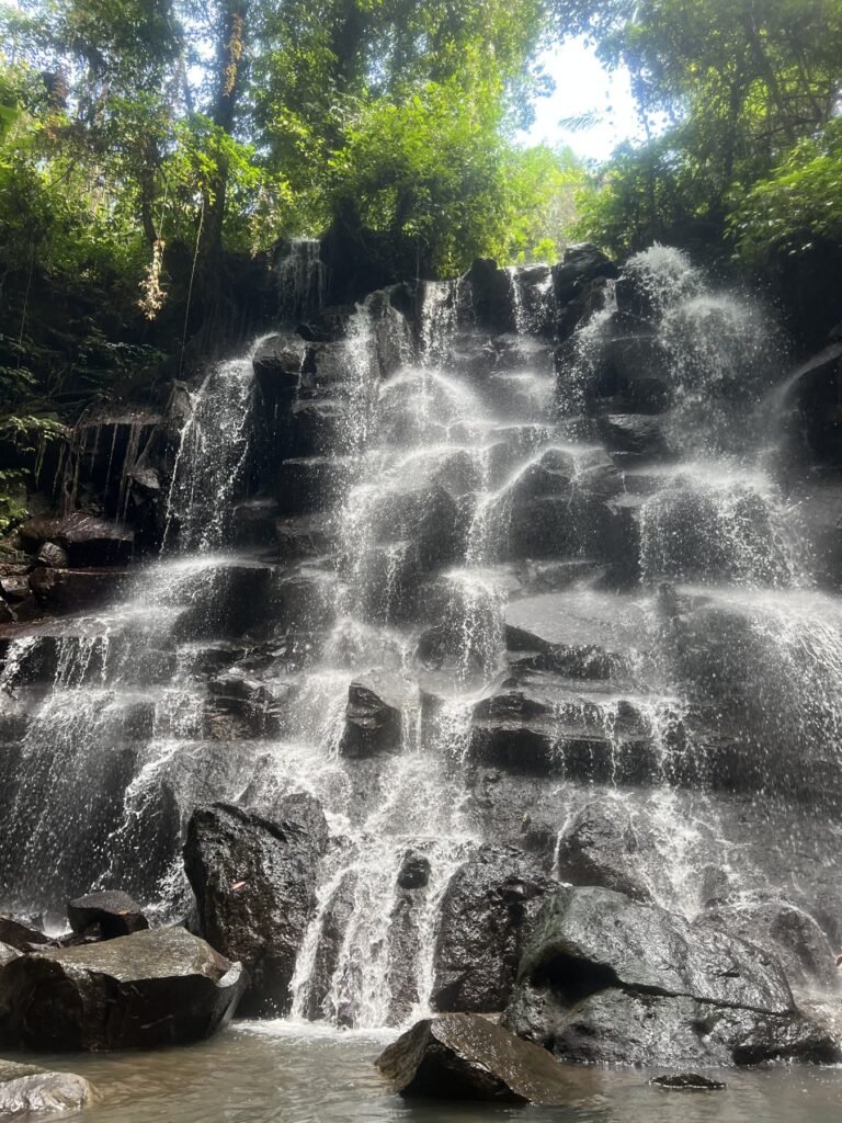 Waterval in trapjes over zwarte lavarotsen in het bos op Bali