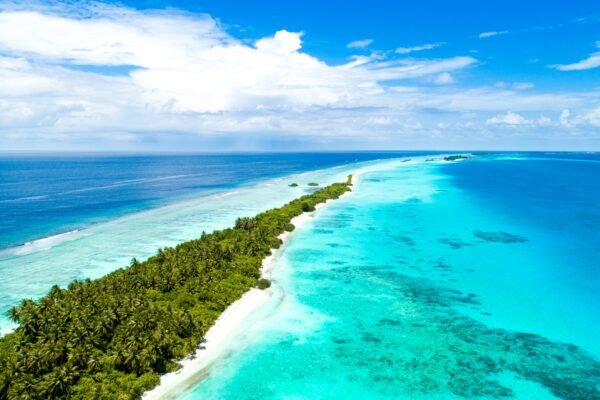 Luchtfoto van een langgerekt eiland met palmen en een koraalrif in turquoise water in de Malediven