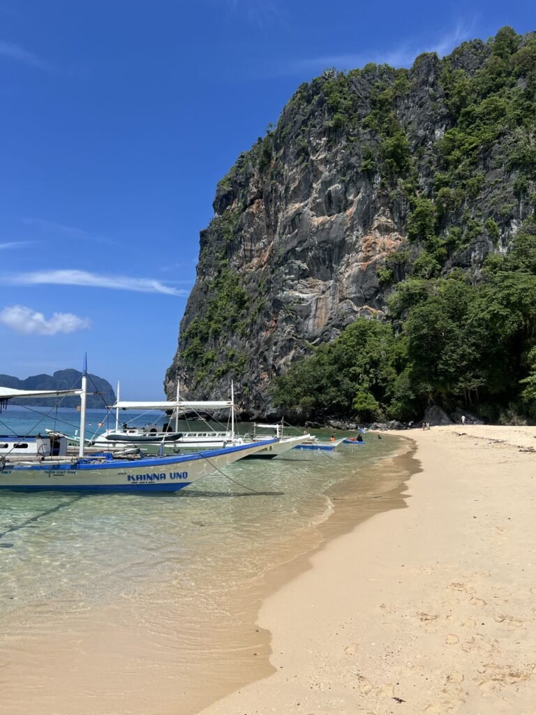 Bangka’s op een strand onder een kalkrots in de Bacuit-baai bij El Nido