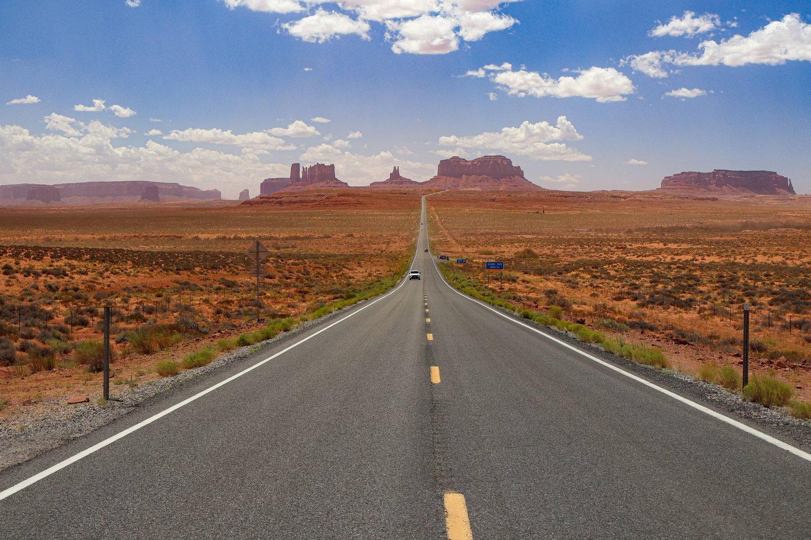 Kaarsrechte weg door Monument Valley met rode tafelbergen aan de horizon