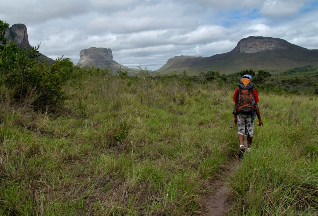 Wandelaar op een pad door het gras met tafelbergen op de achtergrond in de Chapada Diamantina