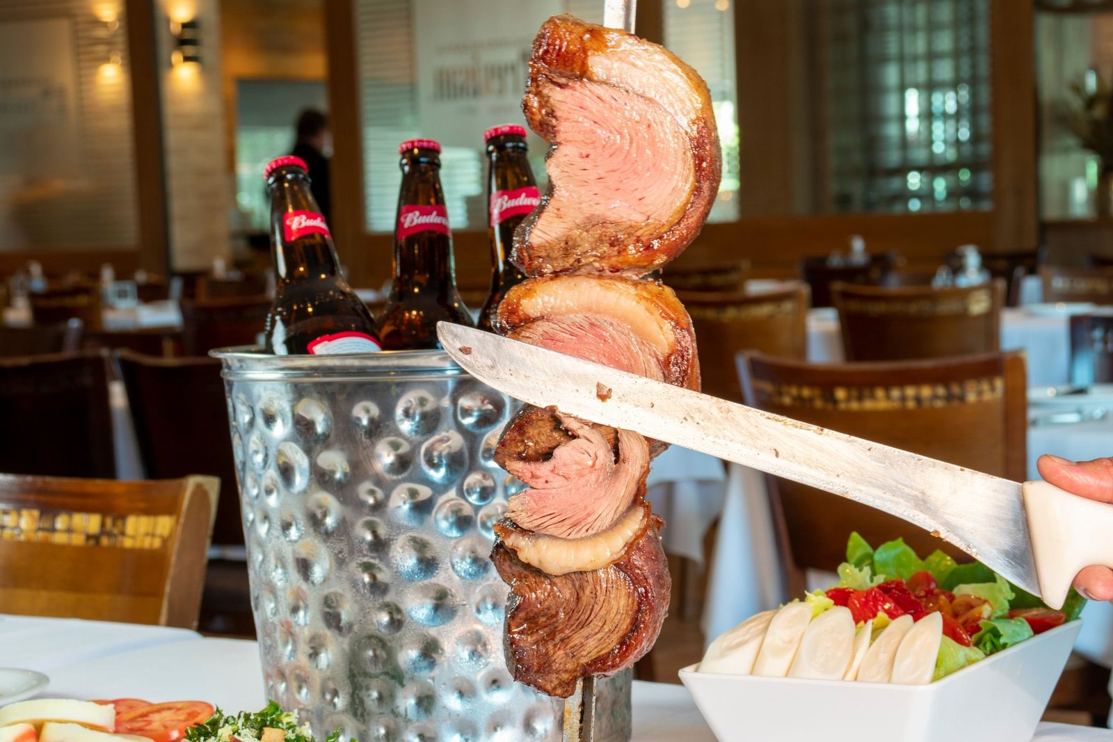 Ober snijdt picanha van het spit in een Braziliaanse churrascaria