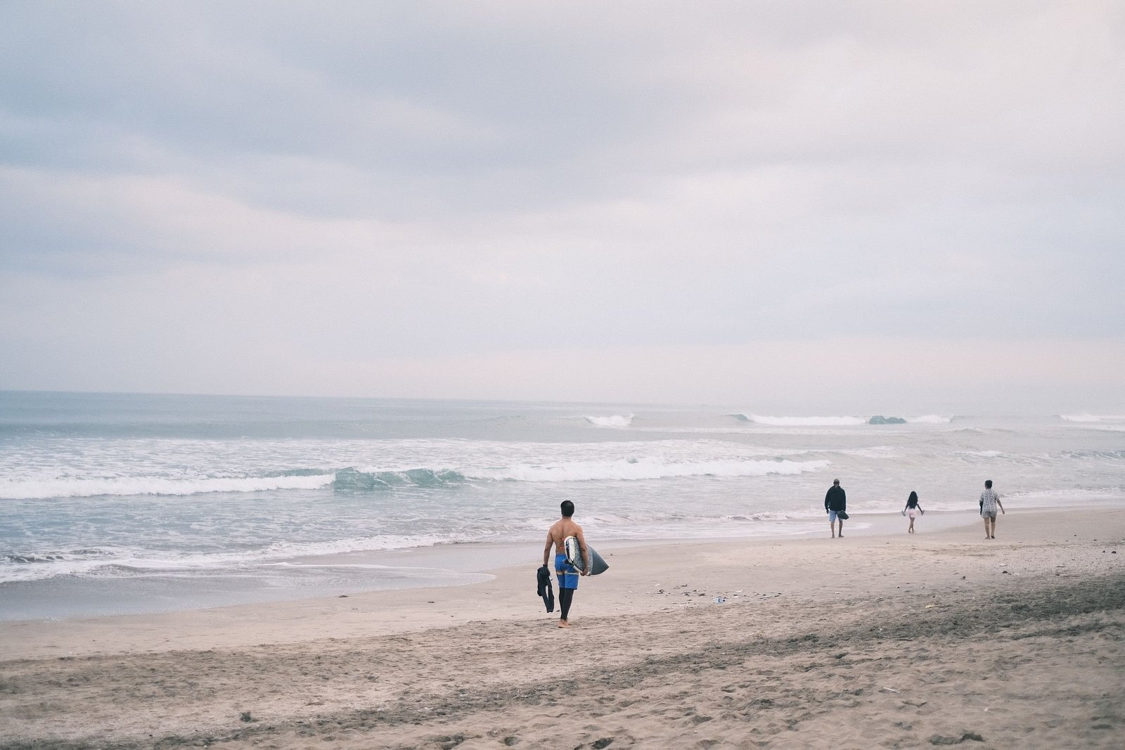 Surfers lopen met hun plank over het strand bij Echo Beach in Canggu