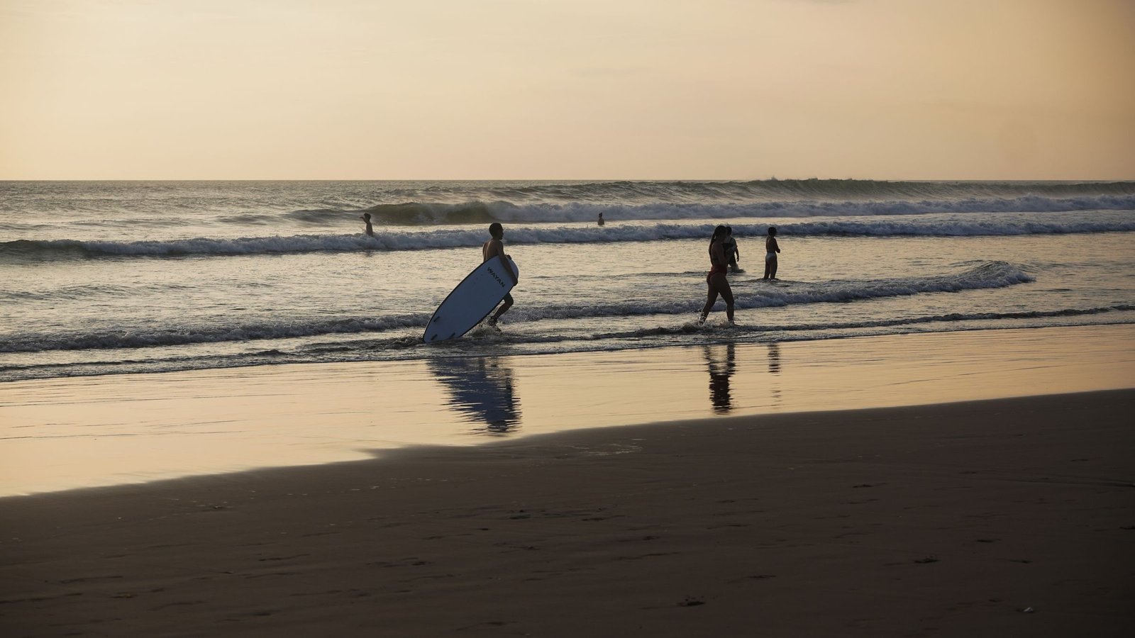 Surfers in de branding bij zonsondergang aan de kust van Canggu