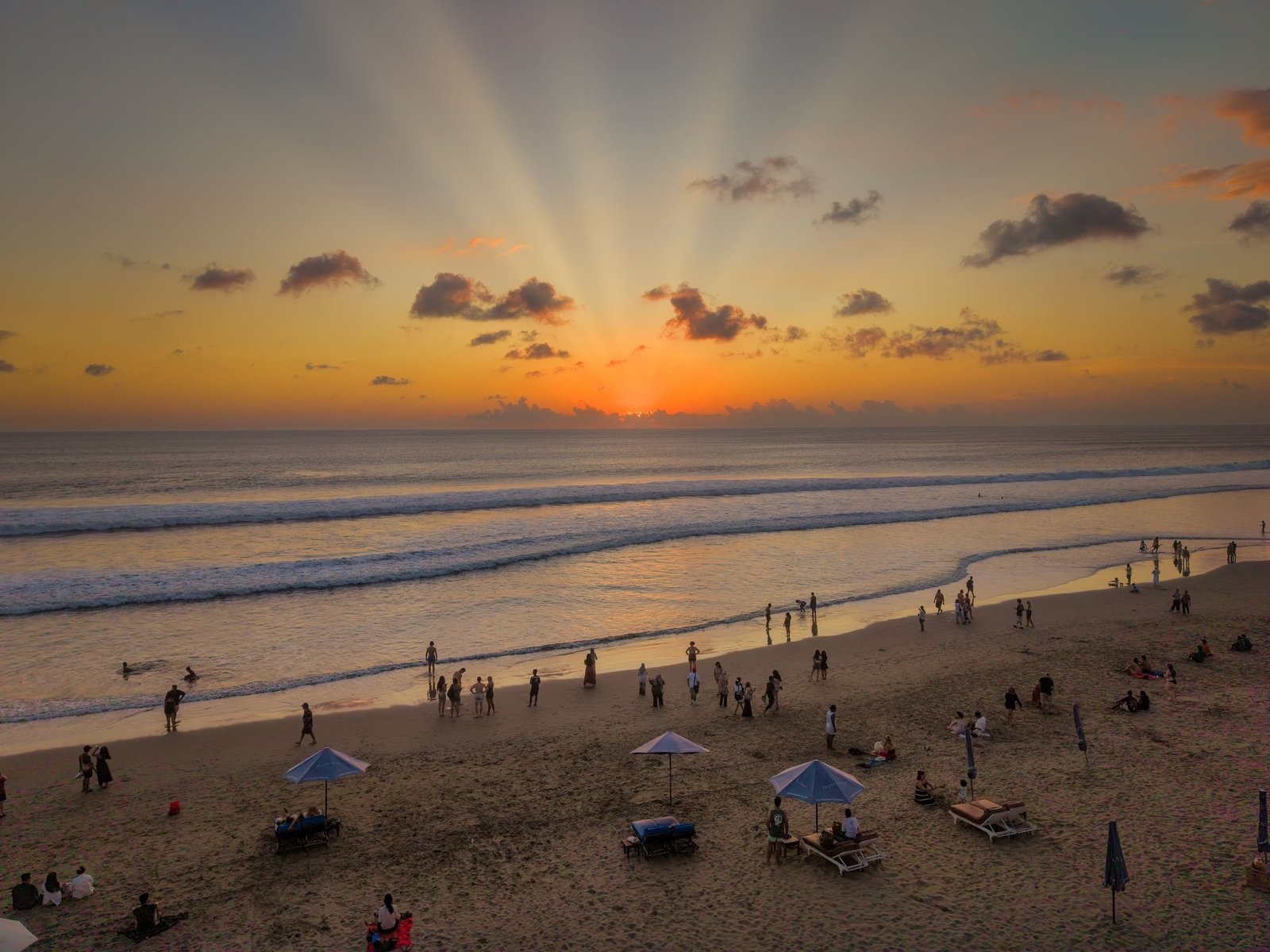 Zonnestralen bij zonsondergang boven het strand van Seminyak