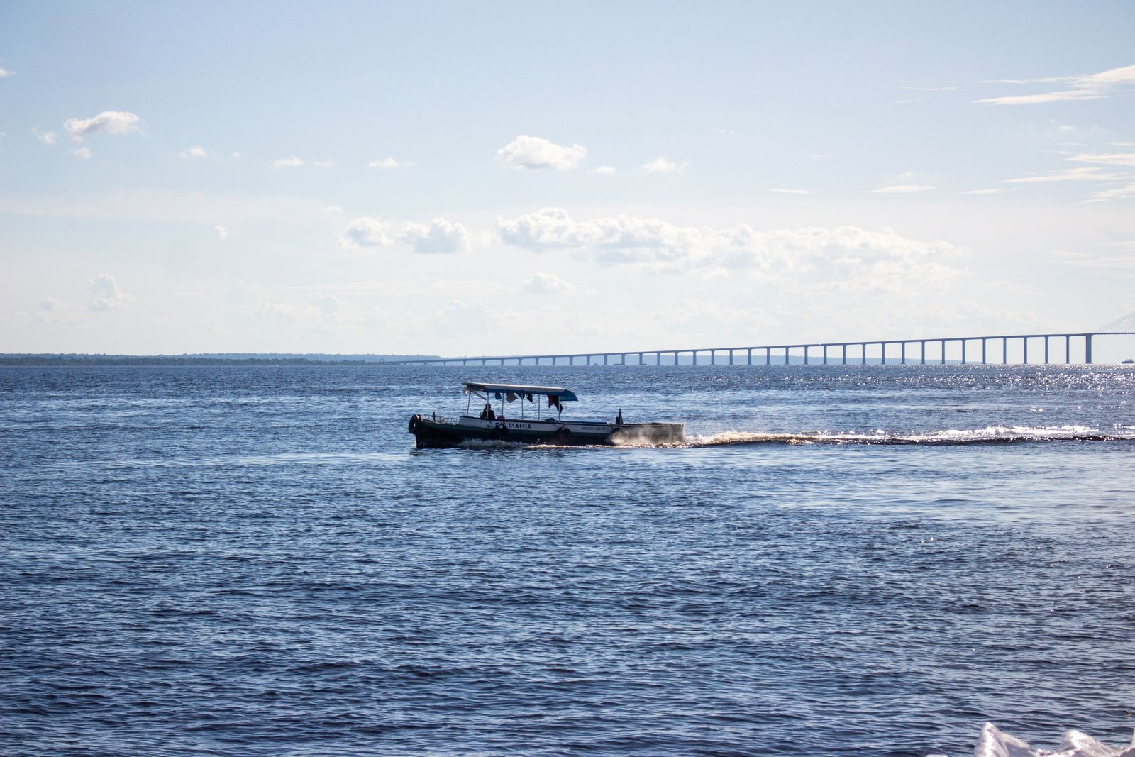 Rivierboot op de Rio Negro bij Manaus met de brug op de achtergrond