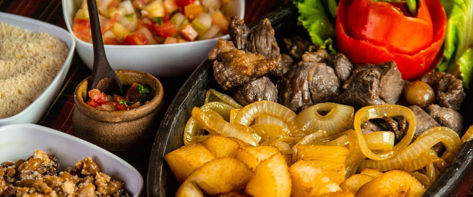 Tafel met Braziliaanse gerechten, rijst, bonen, vlees en gebakken maniok