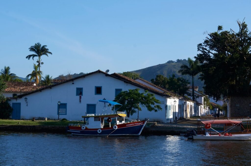 Houten vissersboot aan de kade voor de witte huizen van Paraty