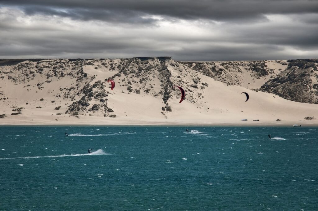 Kitesurfers op zee voor de duinen aan de kust van Ceará