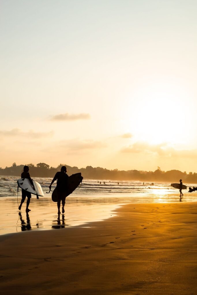 Surfers met hun board op het strand van Weligama bij zonsondergang