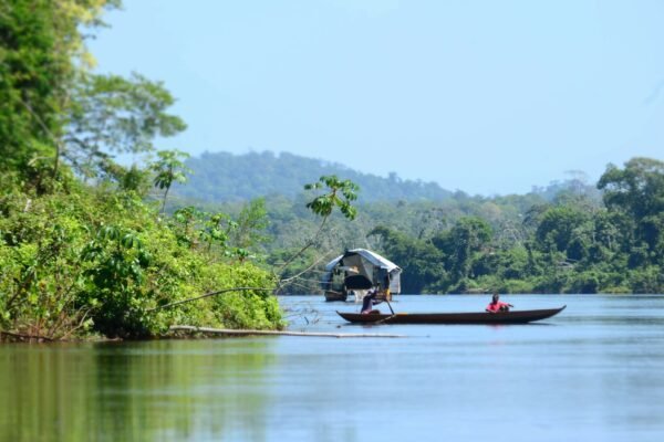 Kleine boot op een brede rivier door het regenwoud van Suriname