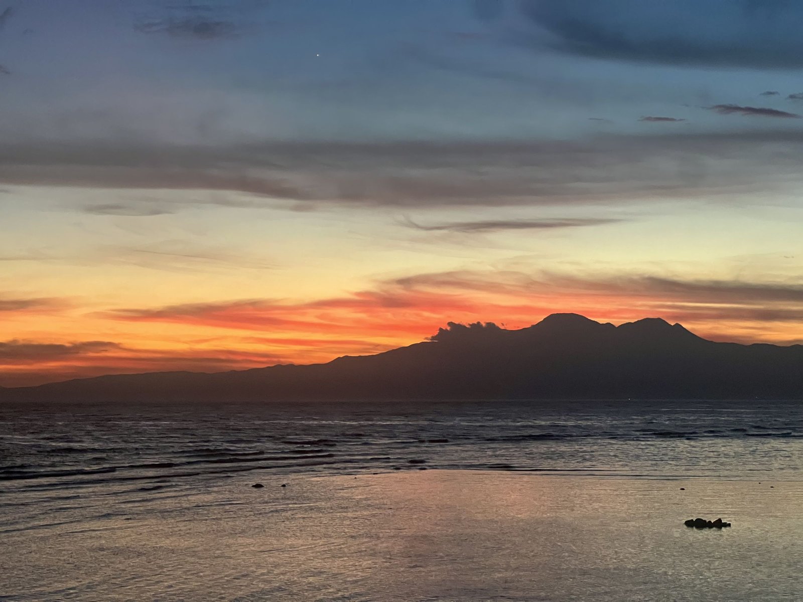 Zonsondergang met bergen aan de horizon vanaf de westkust van Siquijor
