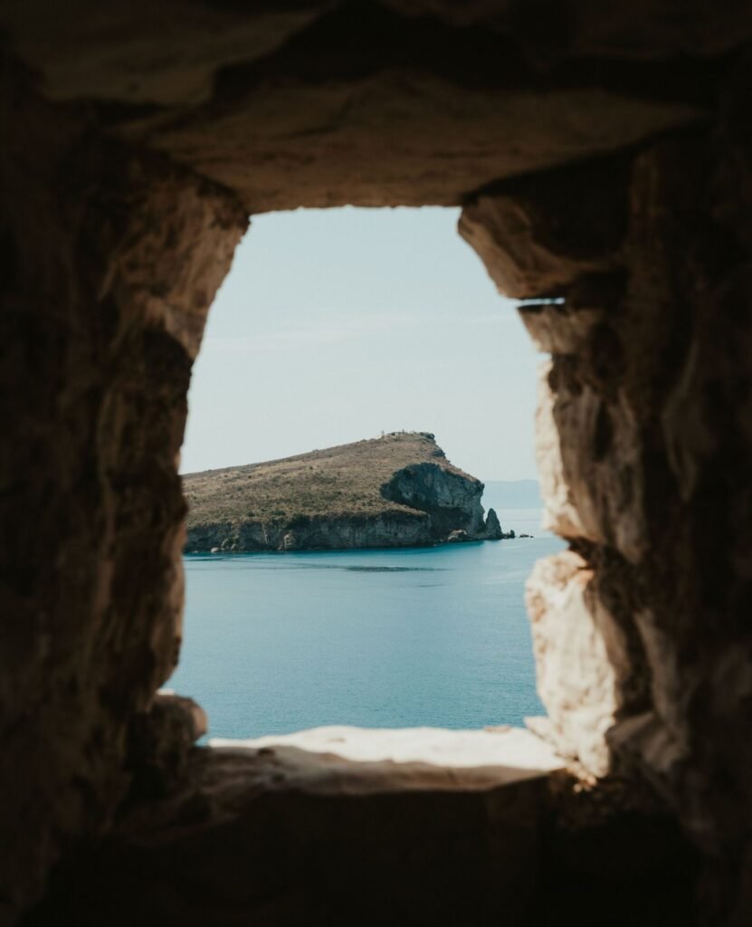 Uitzicht op Porto Palermo door een stenen raam