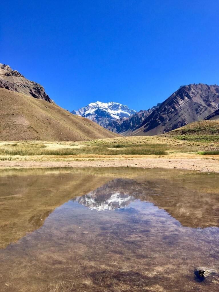 De besneeuwde top van de Aconcagua boven een droog bergdal