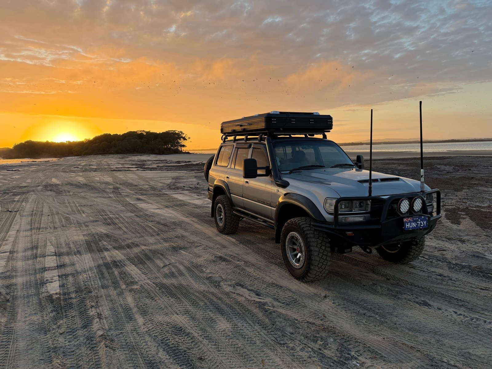 Terreinwagen op het strand bij zonsondergang