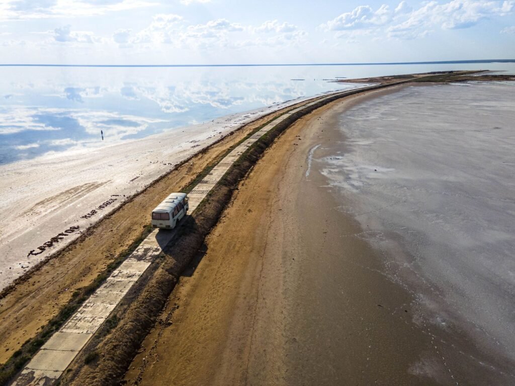 Auto op een zandpad langs het water