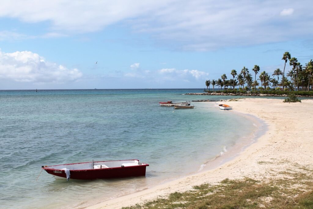 Strand met helder water en een bootje op Aruba