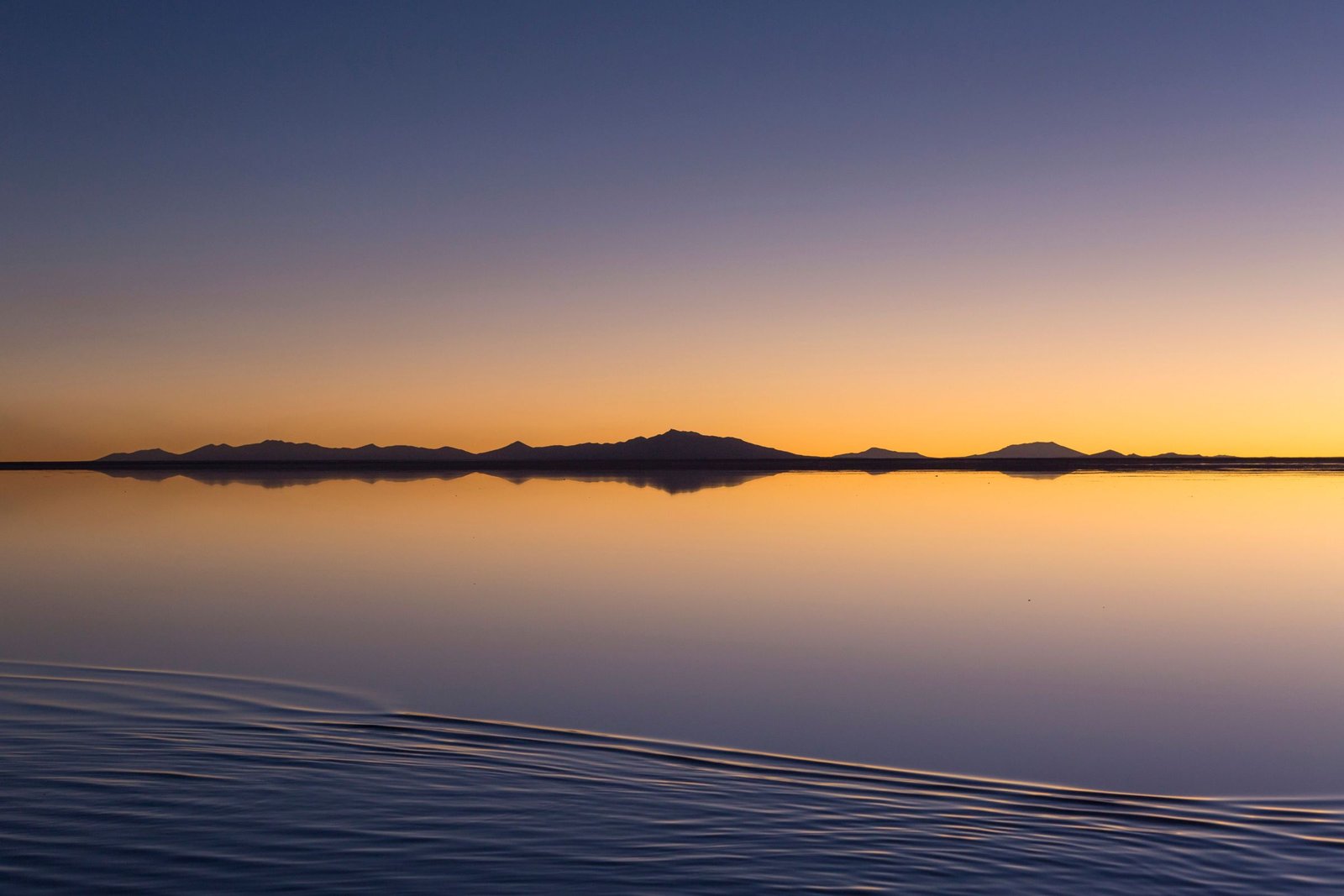Zonsondergang boven de spiegelende Salar de Uyuni