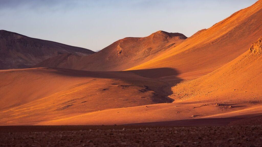 Oranje heuvels in de Atacama-woestijn bij zonsondergang