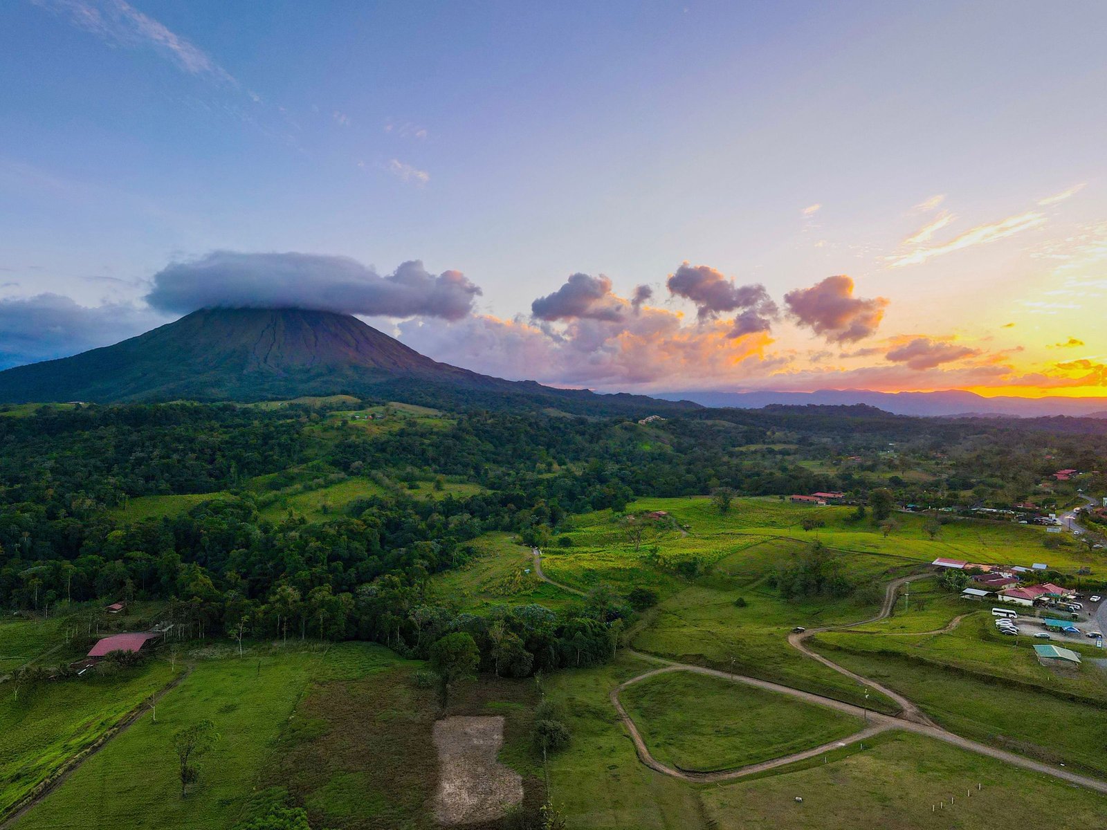 De vulkaan Arenal bij zonsondergang boven het groene land