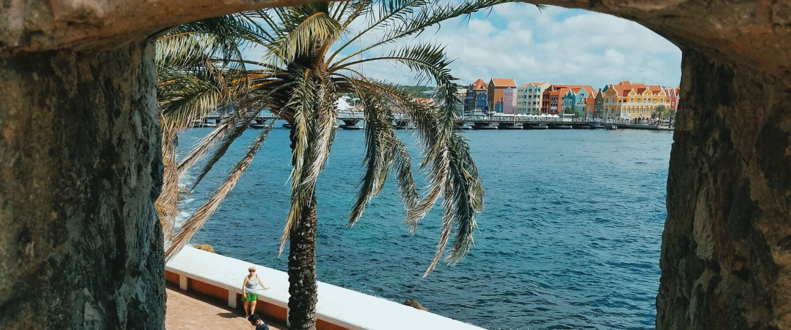 Doorkijk door een stenen boog naar het water in Willemstad