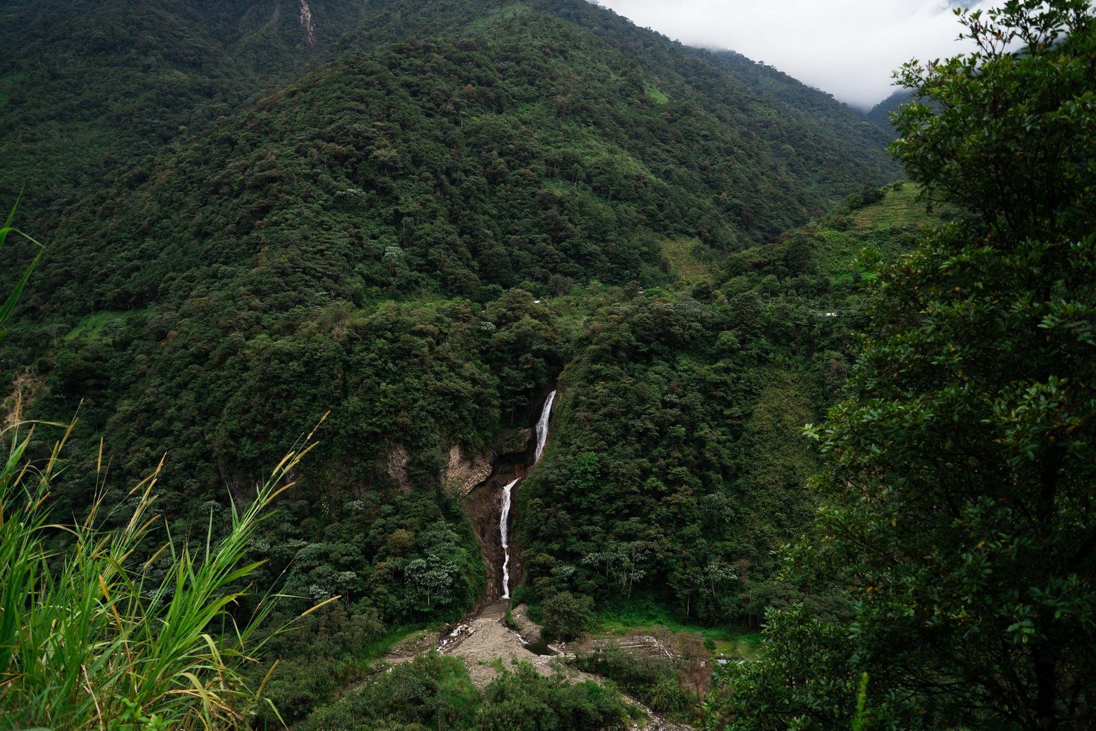 Groene berghellingen met een waterval langs de Ruta de las Cascadas bij Baños
