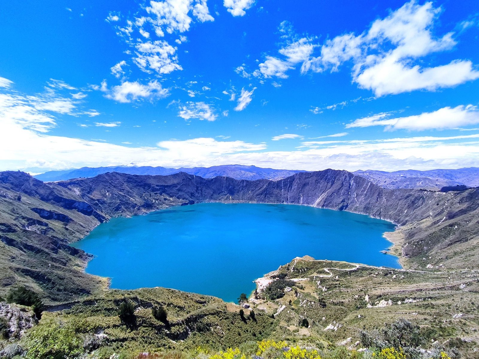 Het turquoise kratermeer van Quilotoa onder een blauwe lucht