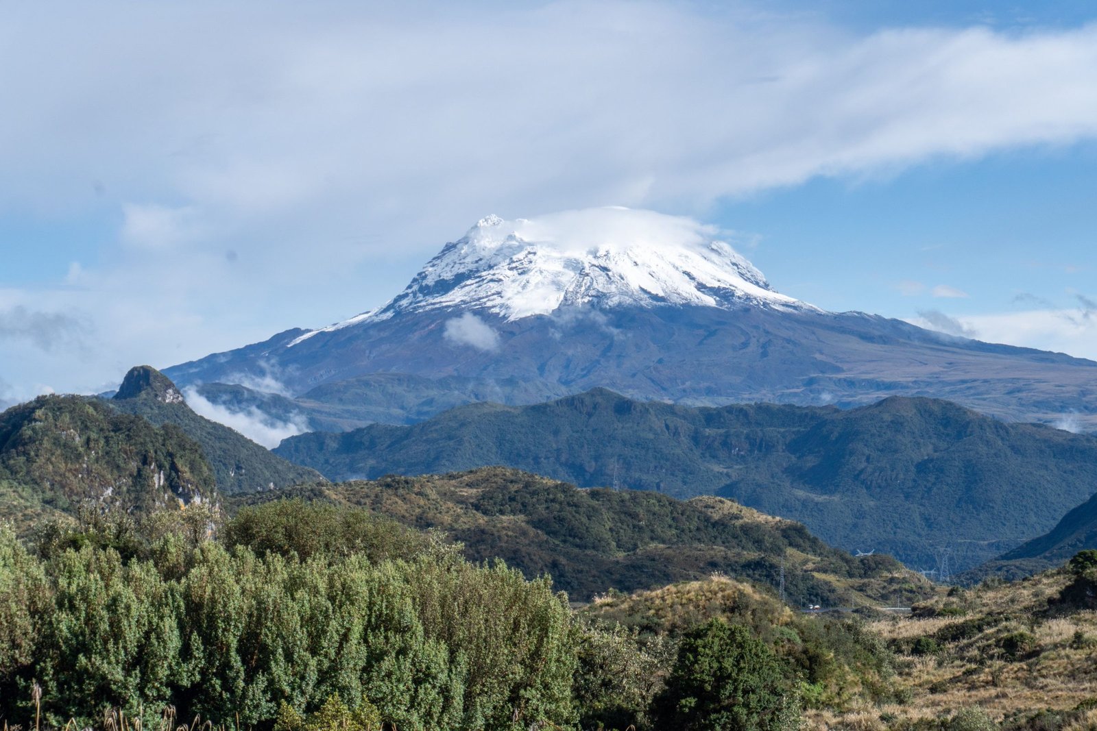 Besneeuwde vulkaan boven groene heuvels in de Andes van Ecuador