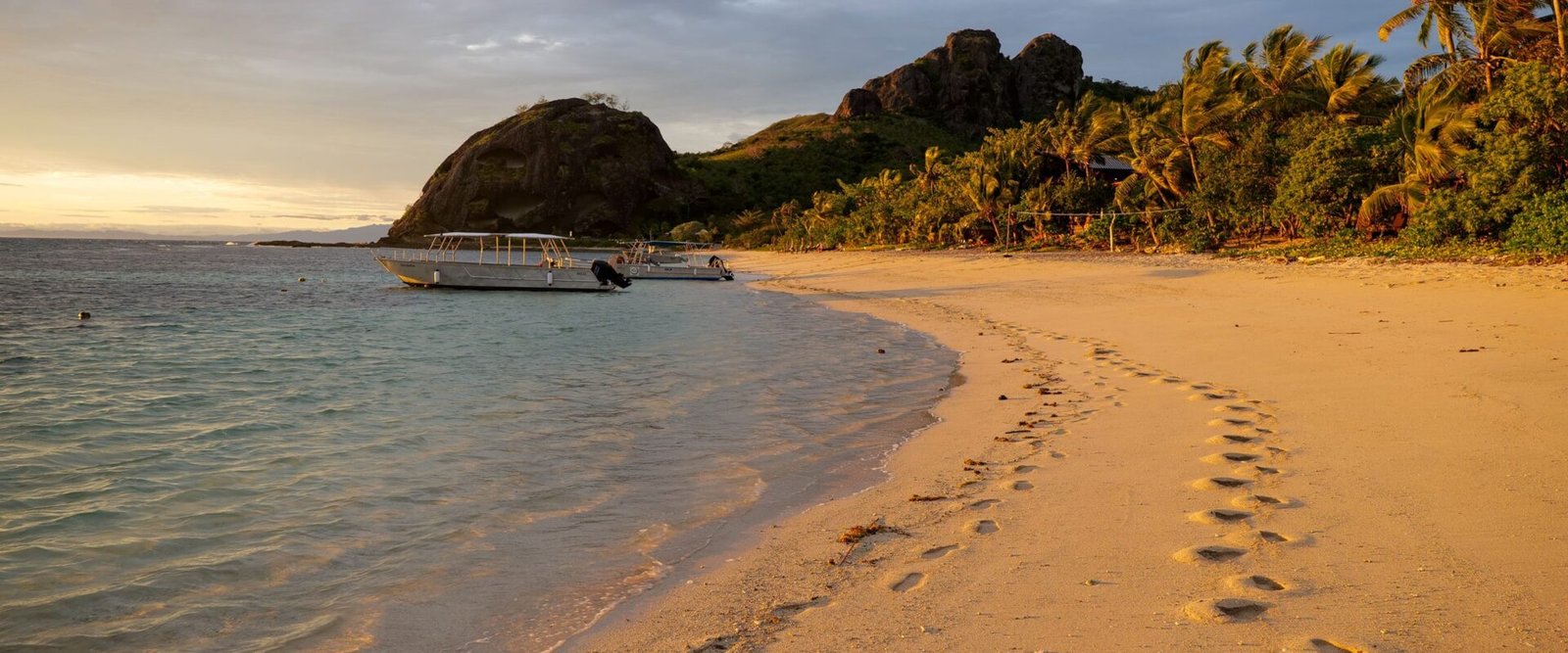 Zandstrand met voetstappen en een rotsige heuvel op een eiland in Fiji