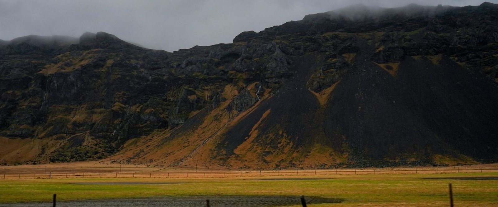 Groene vlakte onder bergen in IJsland