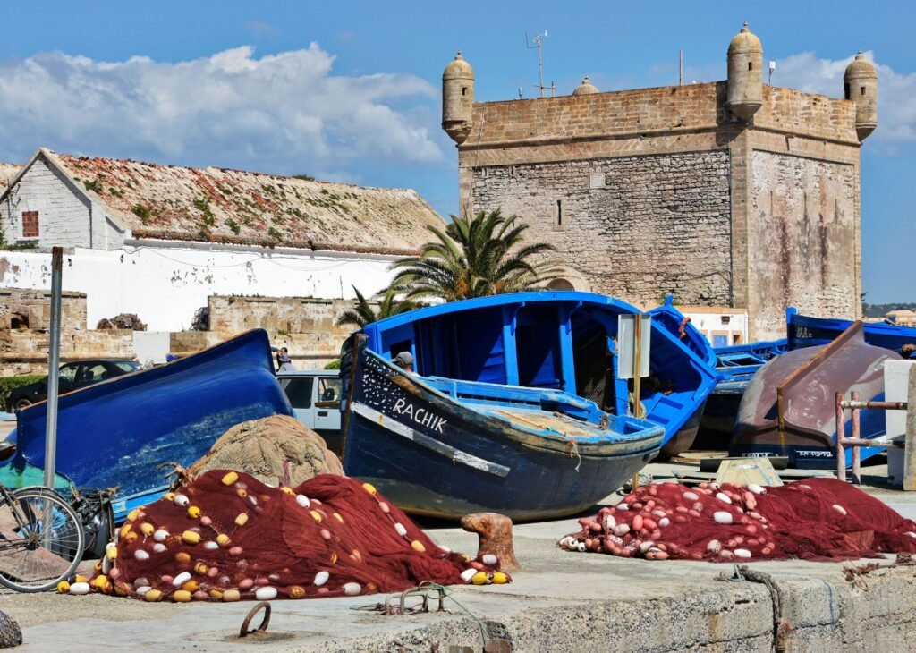 Blauwe vissersboten in de haven van Essaouira met de vestingmuren op de achtergrond