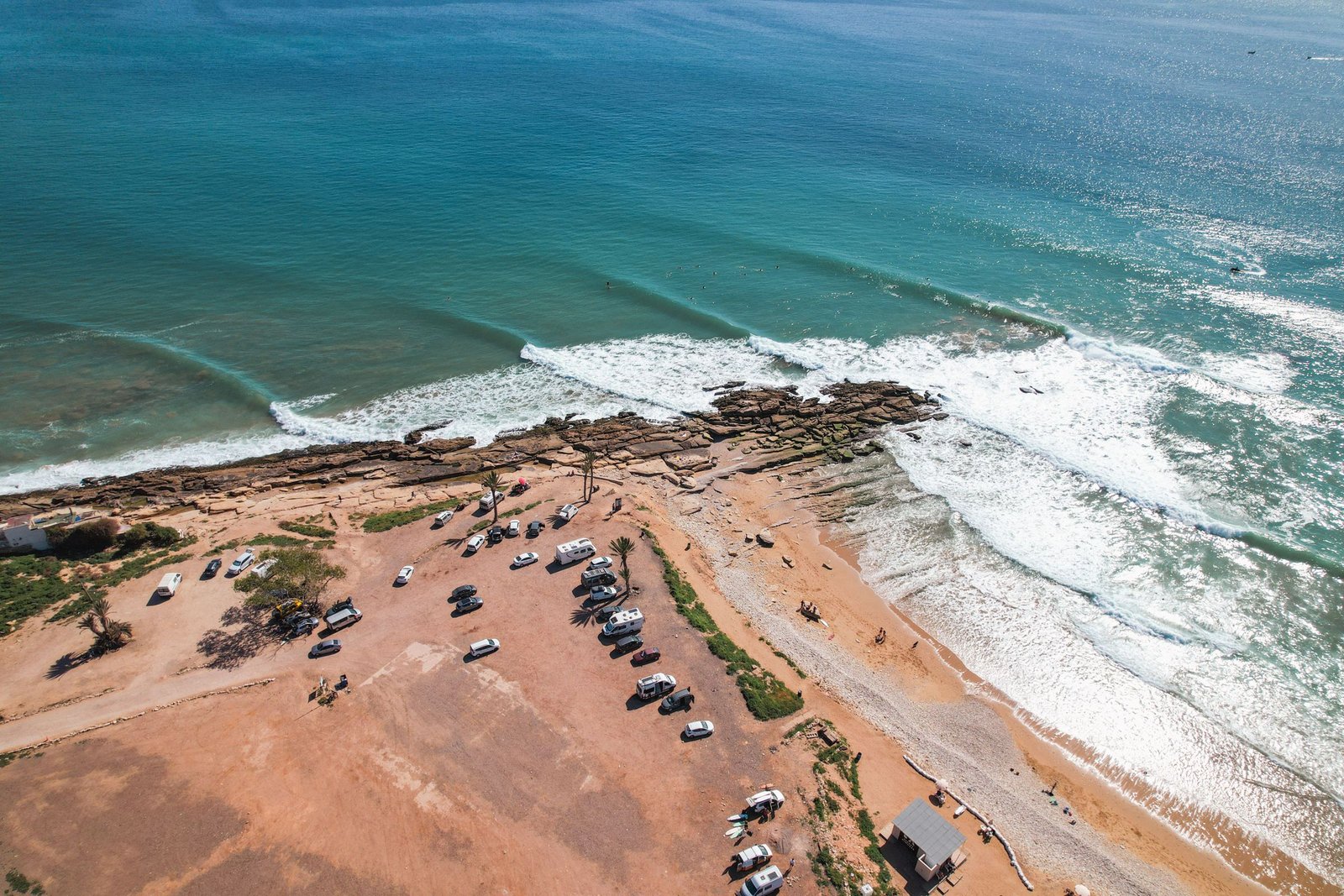 Luchtfoto van de surfkust bij Taghazout met golven die op de rotsen breken