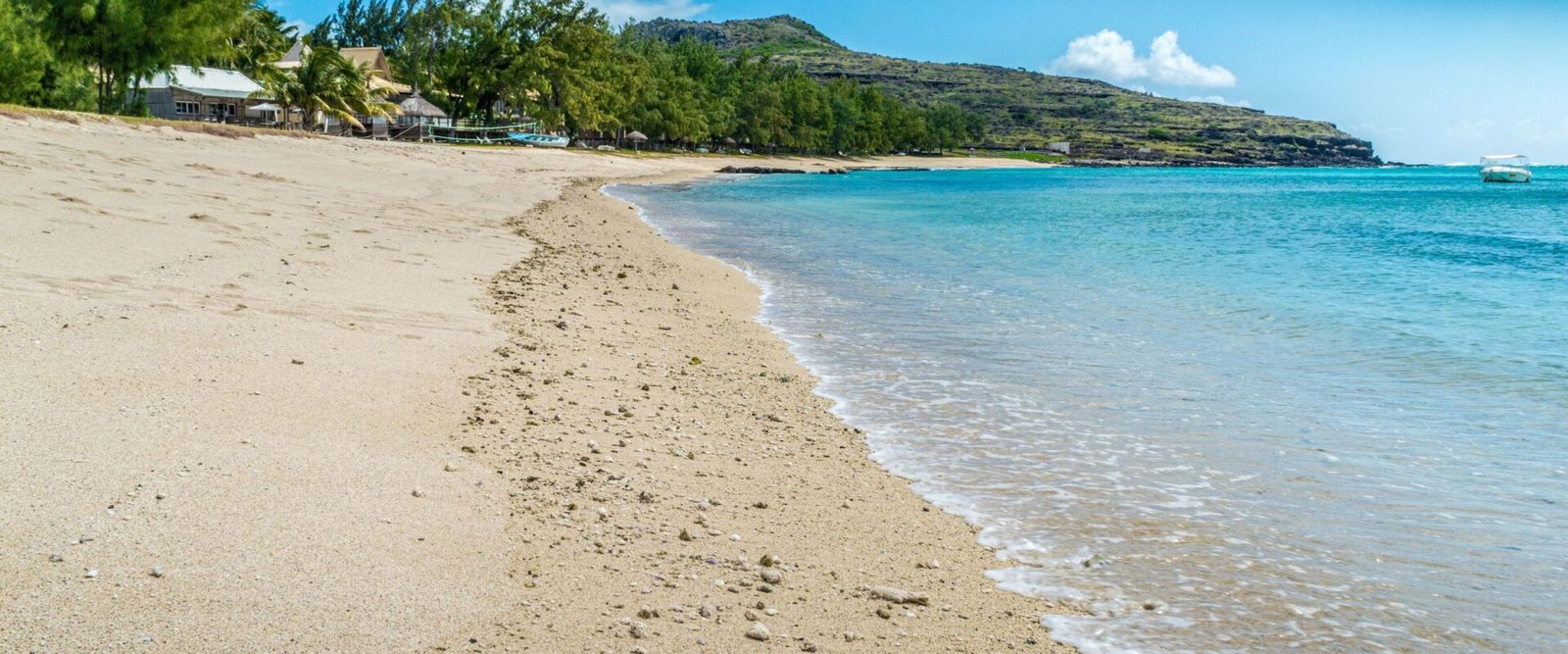Breed zandstrand aan de kust van Mauritius bij helder weer