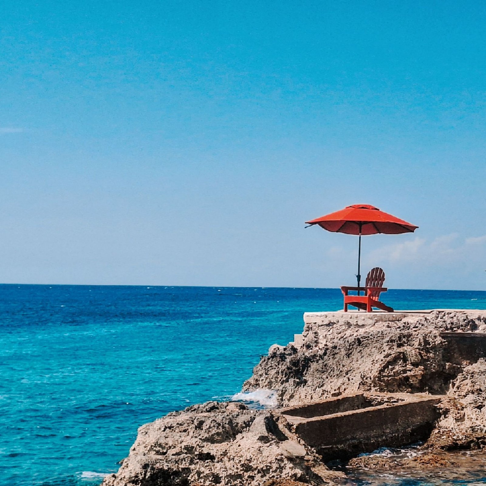 Rode stoel en parasol op de rotsen aan Cozumel