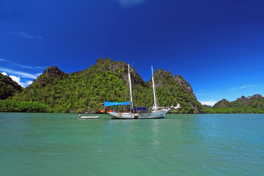 Zeilboot tussen kalkrotsen bij Langkawi