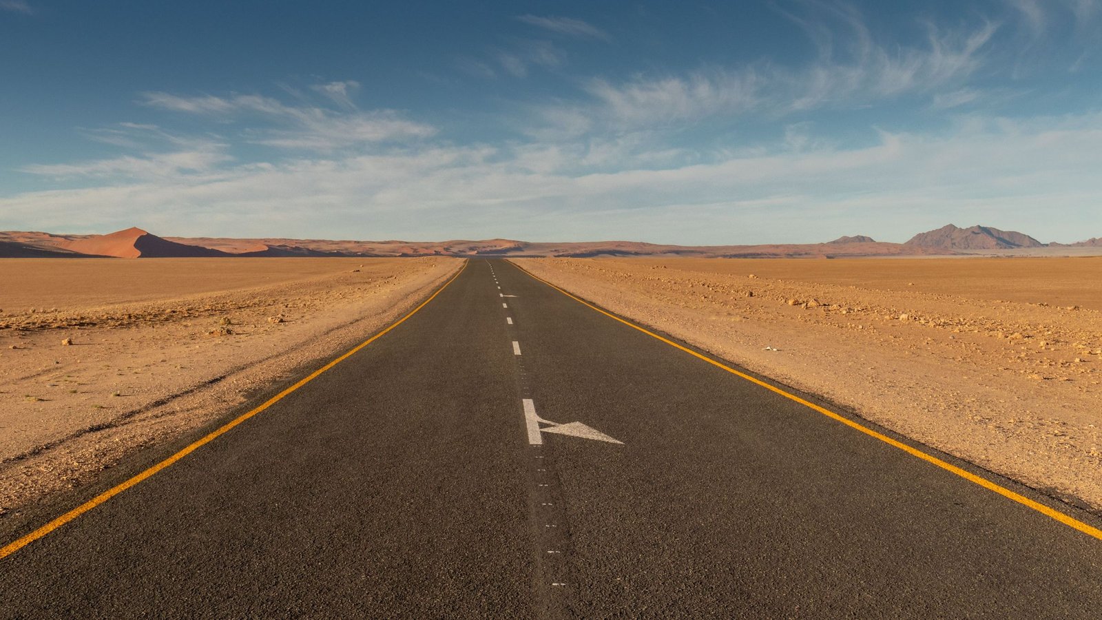 Lange rechte weg door de woestijn van Namibië