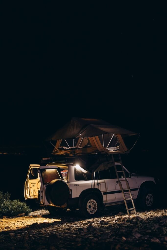 Terreinwagen met daktent op een camping onder de sterrenhemel