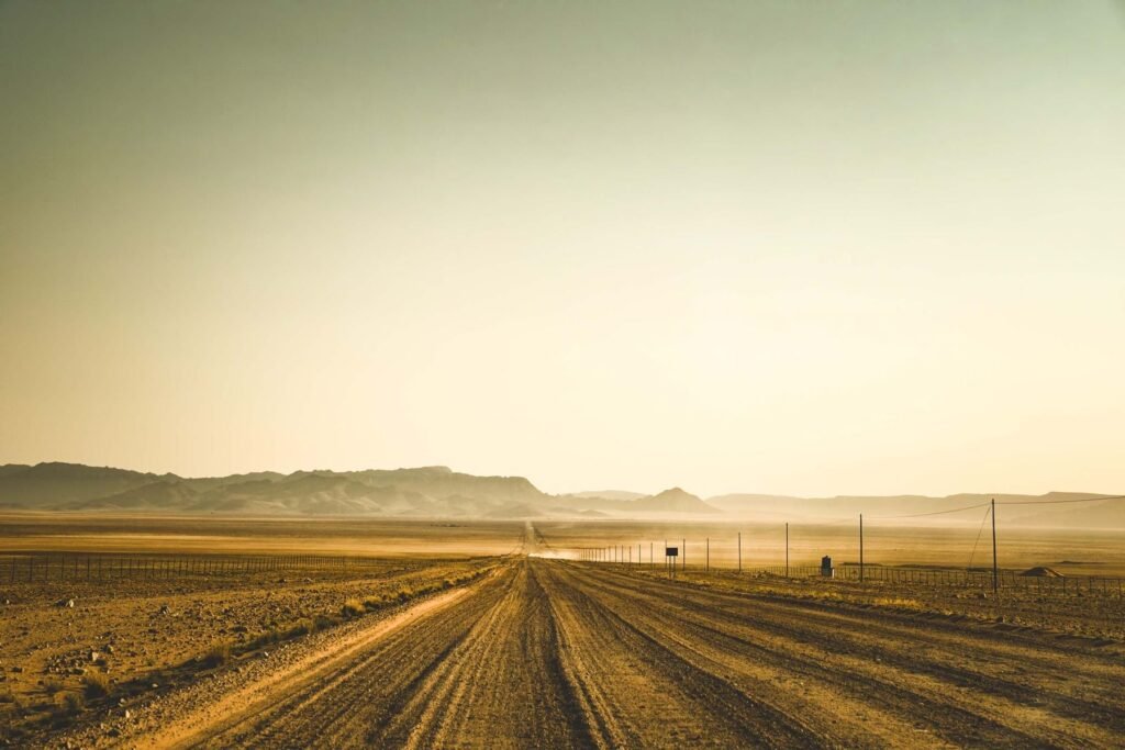 Terreinwagen met een stofwolk op een grindweg door Namibië