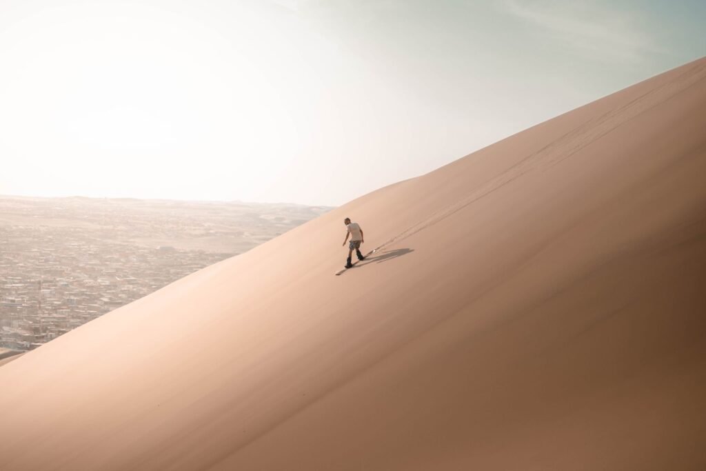 Sandboard op de top van een steile zandduin in de woestijn