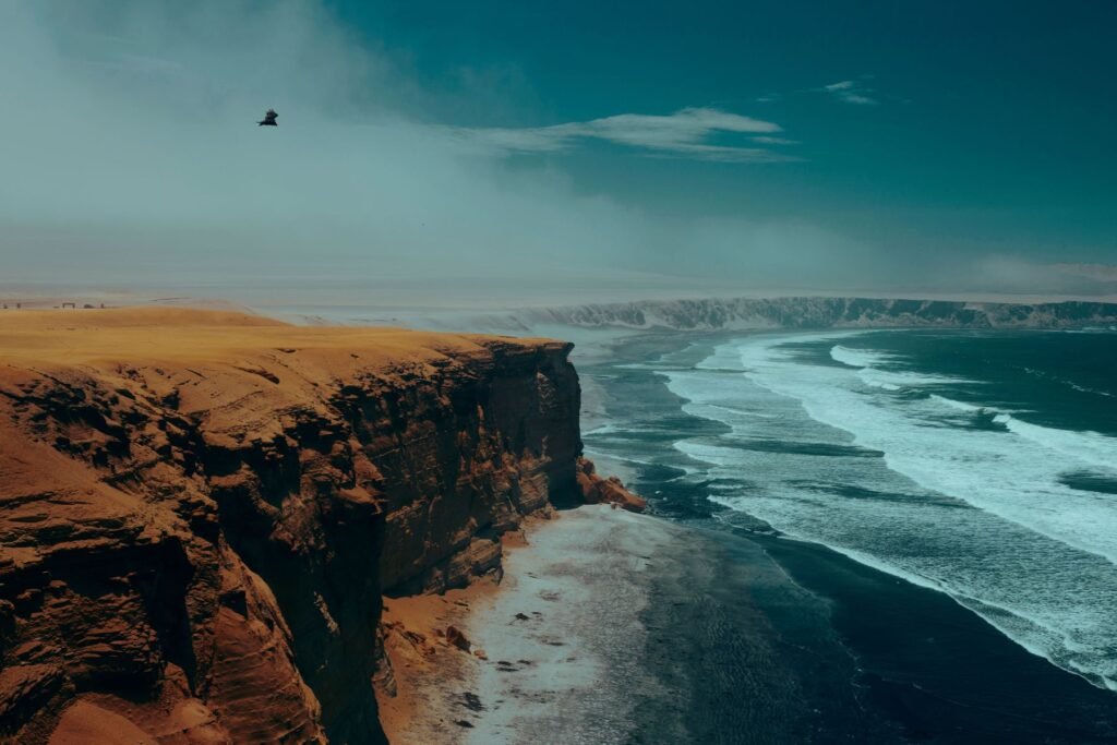 Strand met rood zand onder woestijnkliffen in het reservaat van Paracas